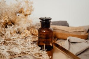 Amber glass bottle surrounded by dried flowers on a rustic surface, creating a vintage aesthetic.