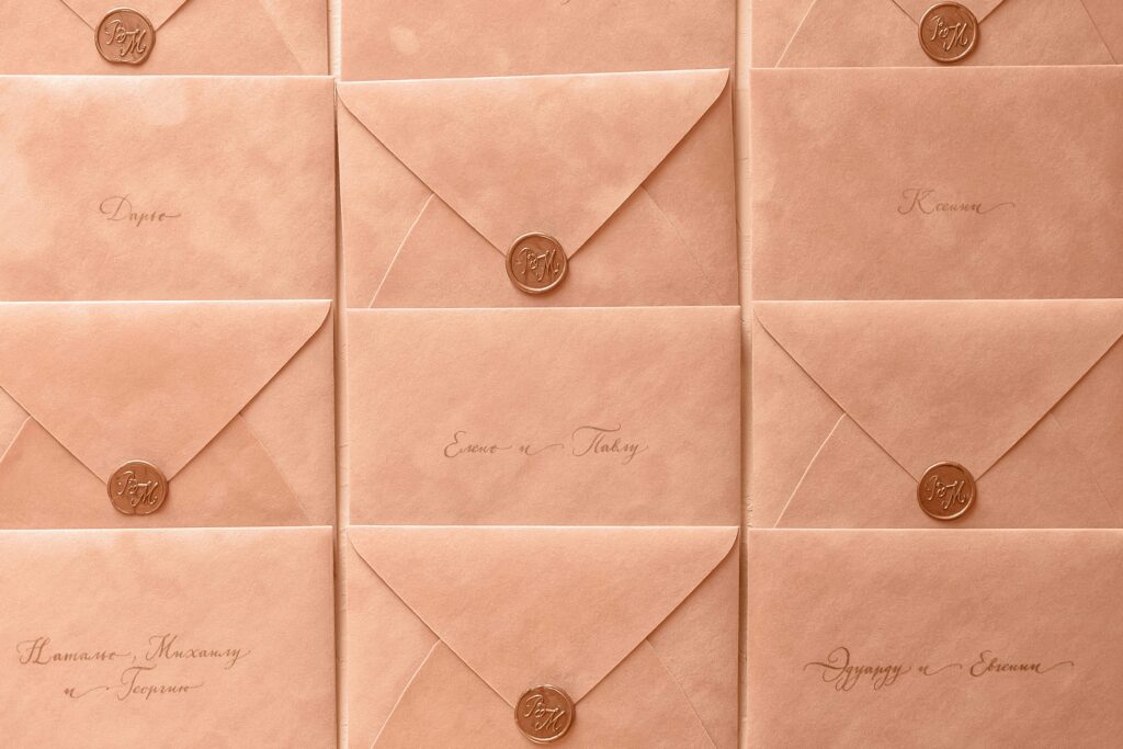 Rows of peach-colored envelopes sealed with wax, featuring elegant calligraphy.