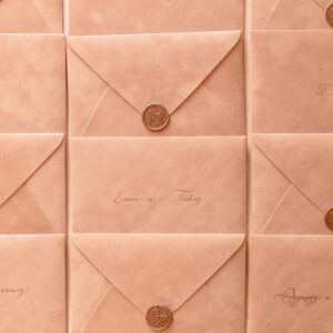 Rows of peach-colored envelopes sealed with wax, featuring elegant calligraphy.