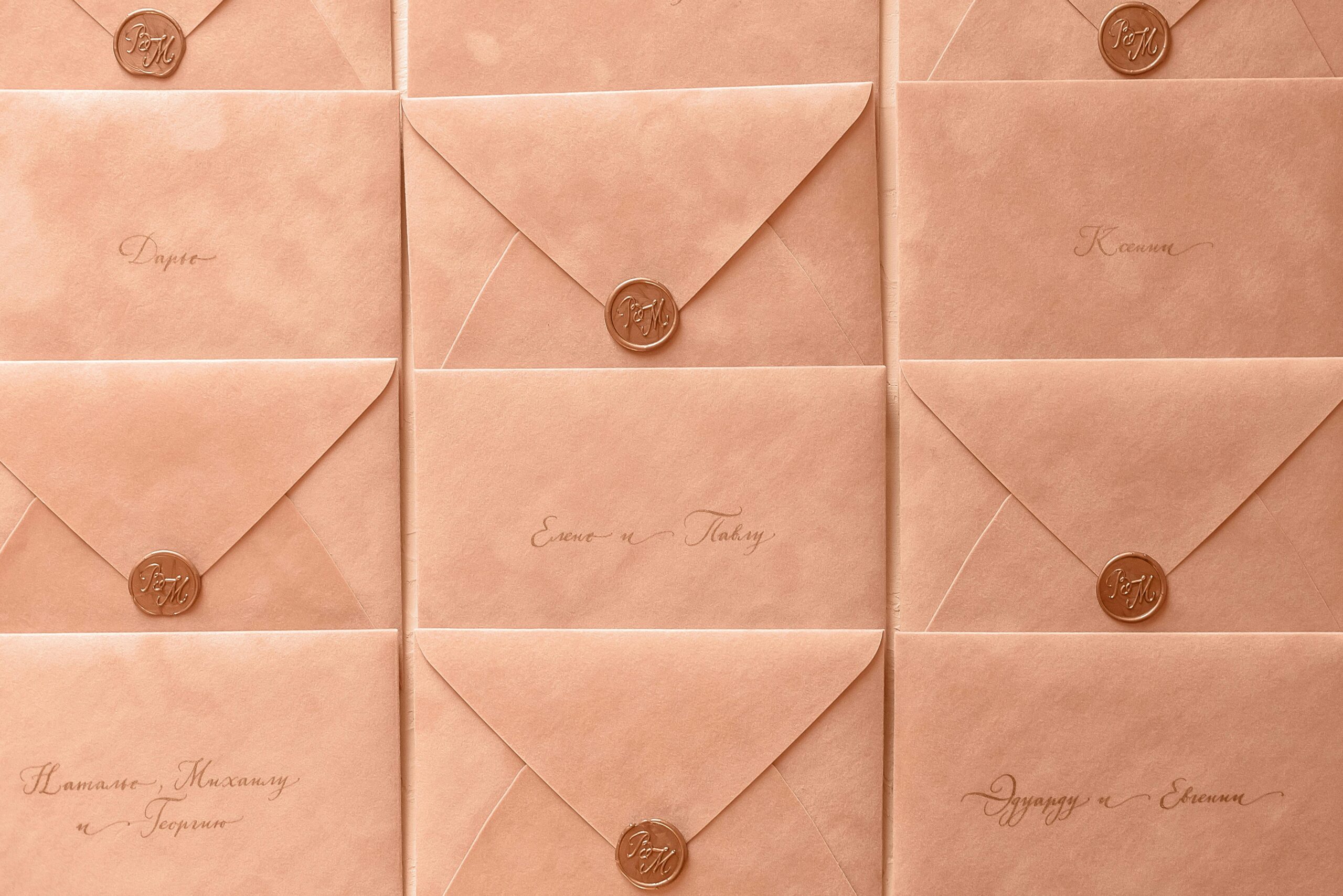Rows of peach-colored envelopes sealed with wax, featuring elegant calligraphy.